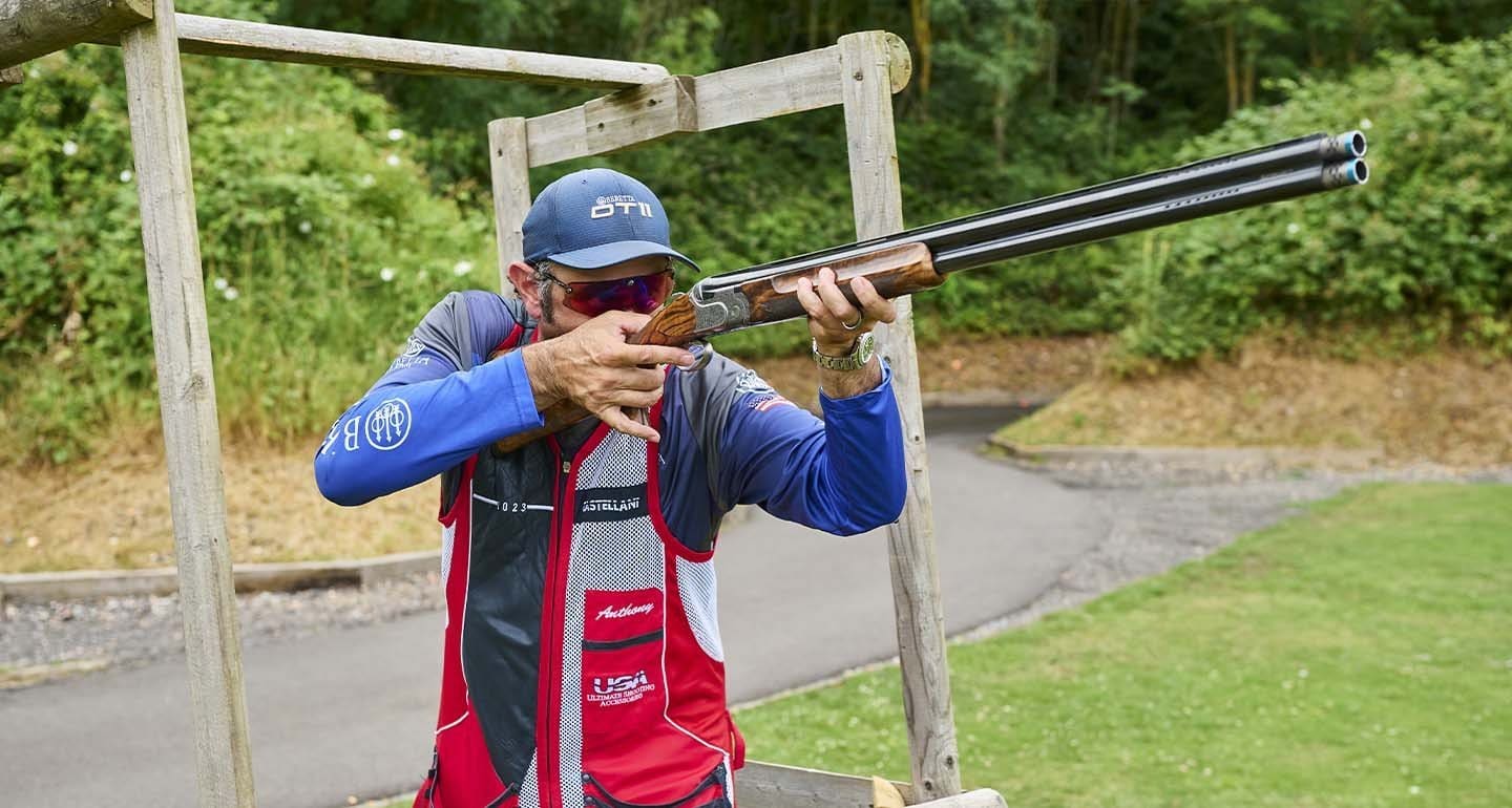 Shooter firing a shotgun from the shoulder at an outdoor range