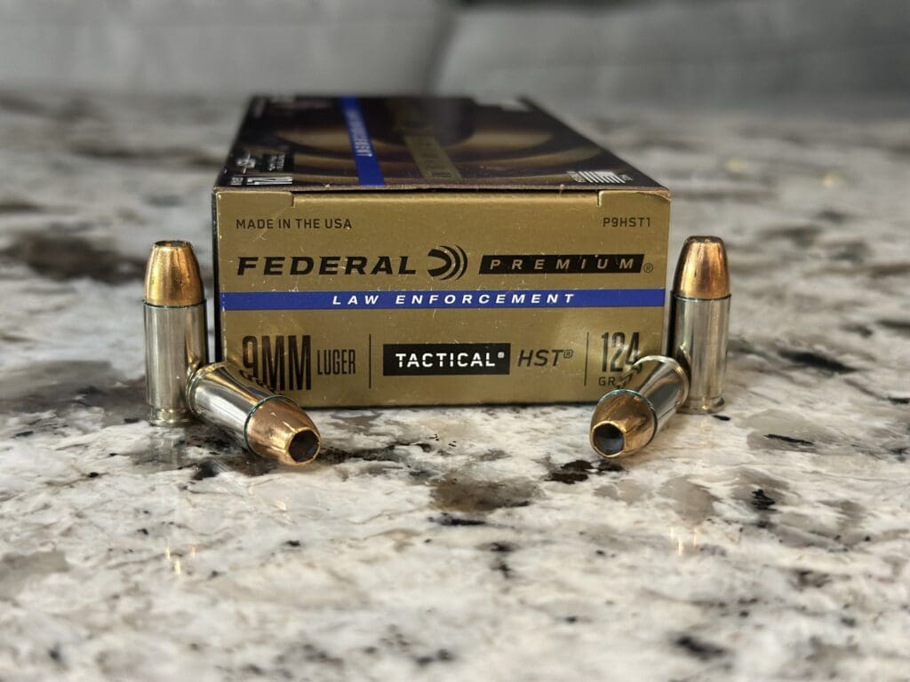 Box of Federal Premium Law Enforcement 9mm Luger 124 grain HST ammunition with four hollow point rounds on a granite countertop